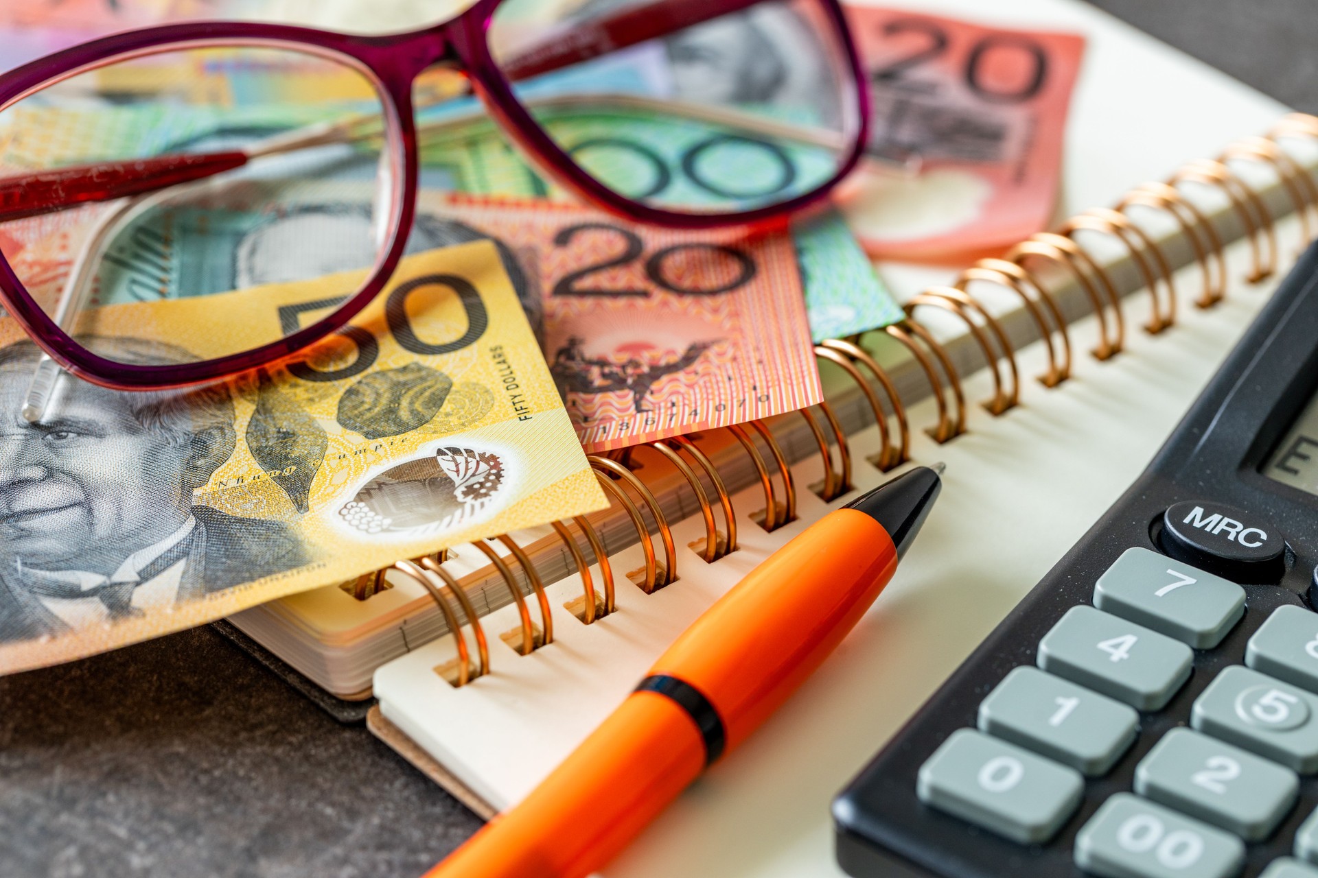 Australia financial settlement. Australian dollars, notebook, reading glasses, calculator and pen, income and expenses, household budget, financial analysis, tax settlement