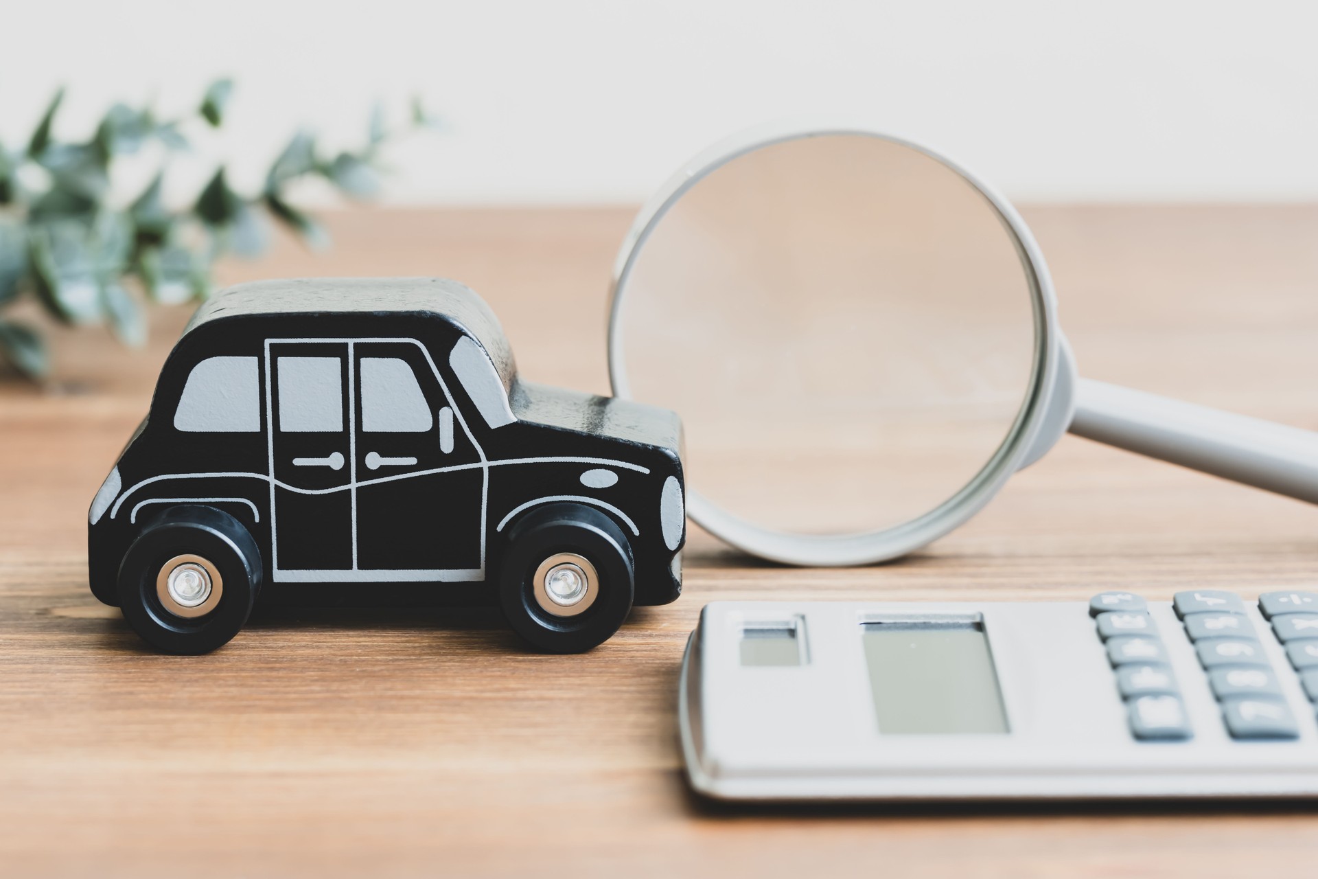 Minicar, calculator and magnifying glass. An image of a car and money.